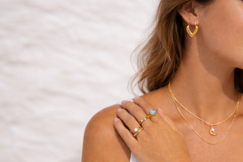 Getragener Goldschmuck mit Ohrringen, Halsketten und Ringen in einem eleganten Sommer-Look von Hesperelle